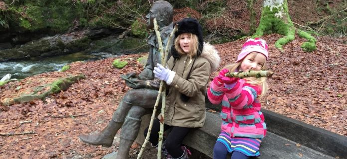 McKelvie girls sitting with the Robert Burns statue in the Birks of Aberfeldy